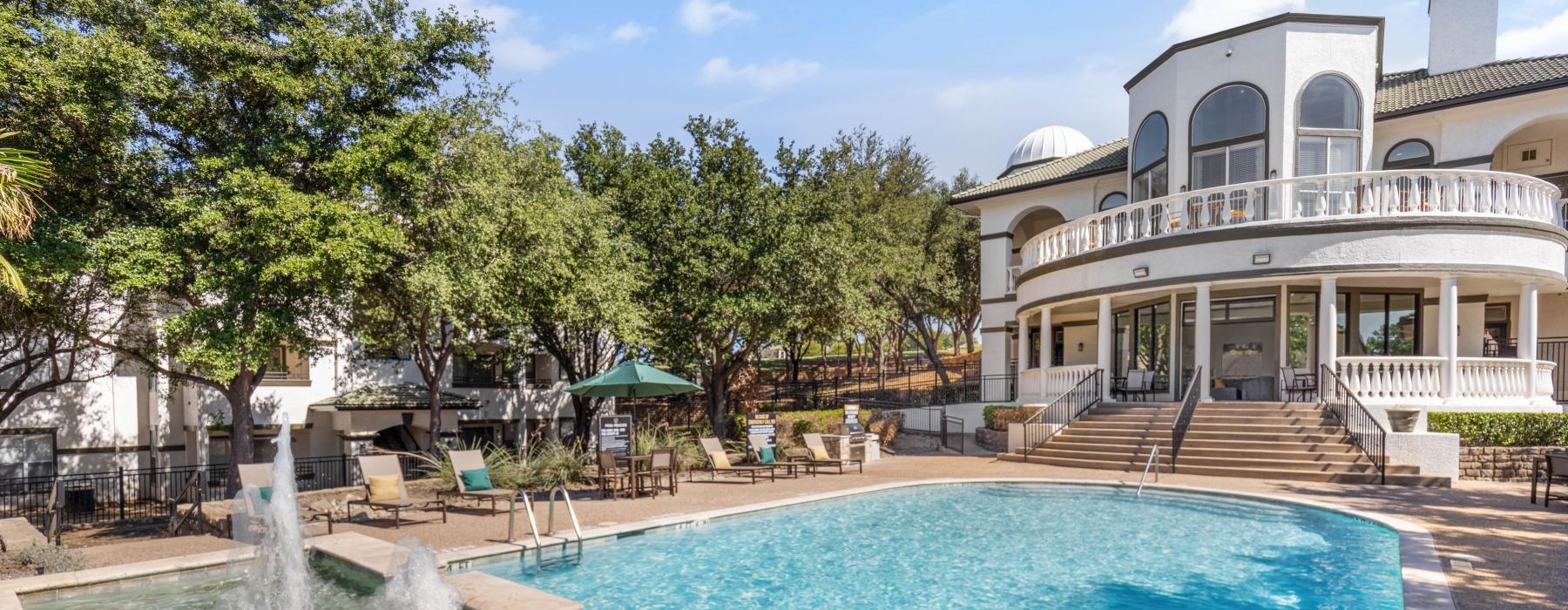 a pool with a fountain in front of a building