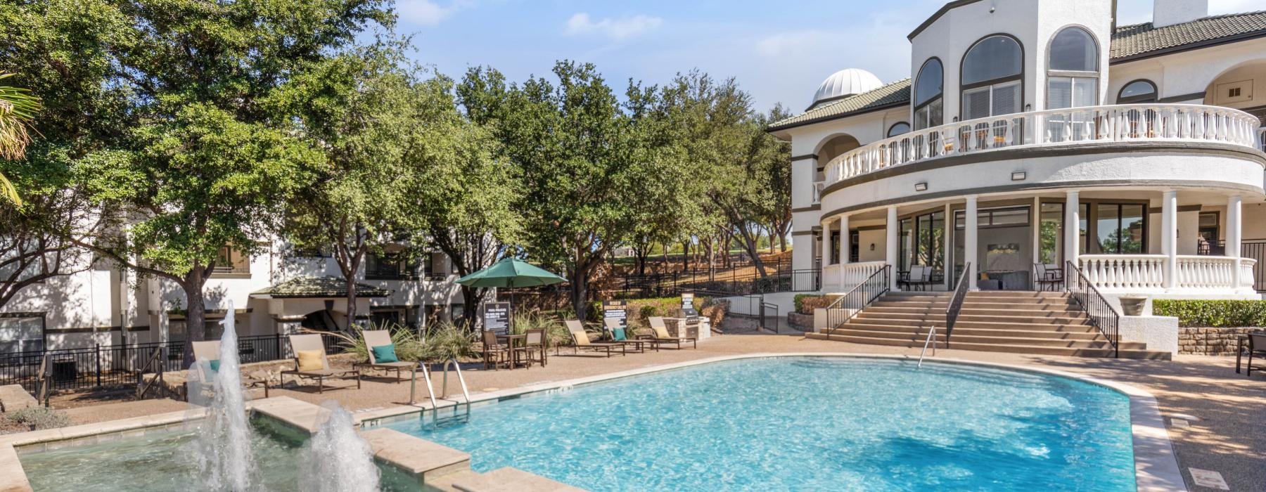 a pool with a fountain in front of a building